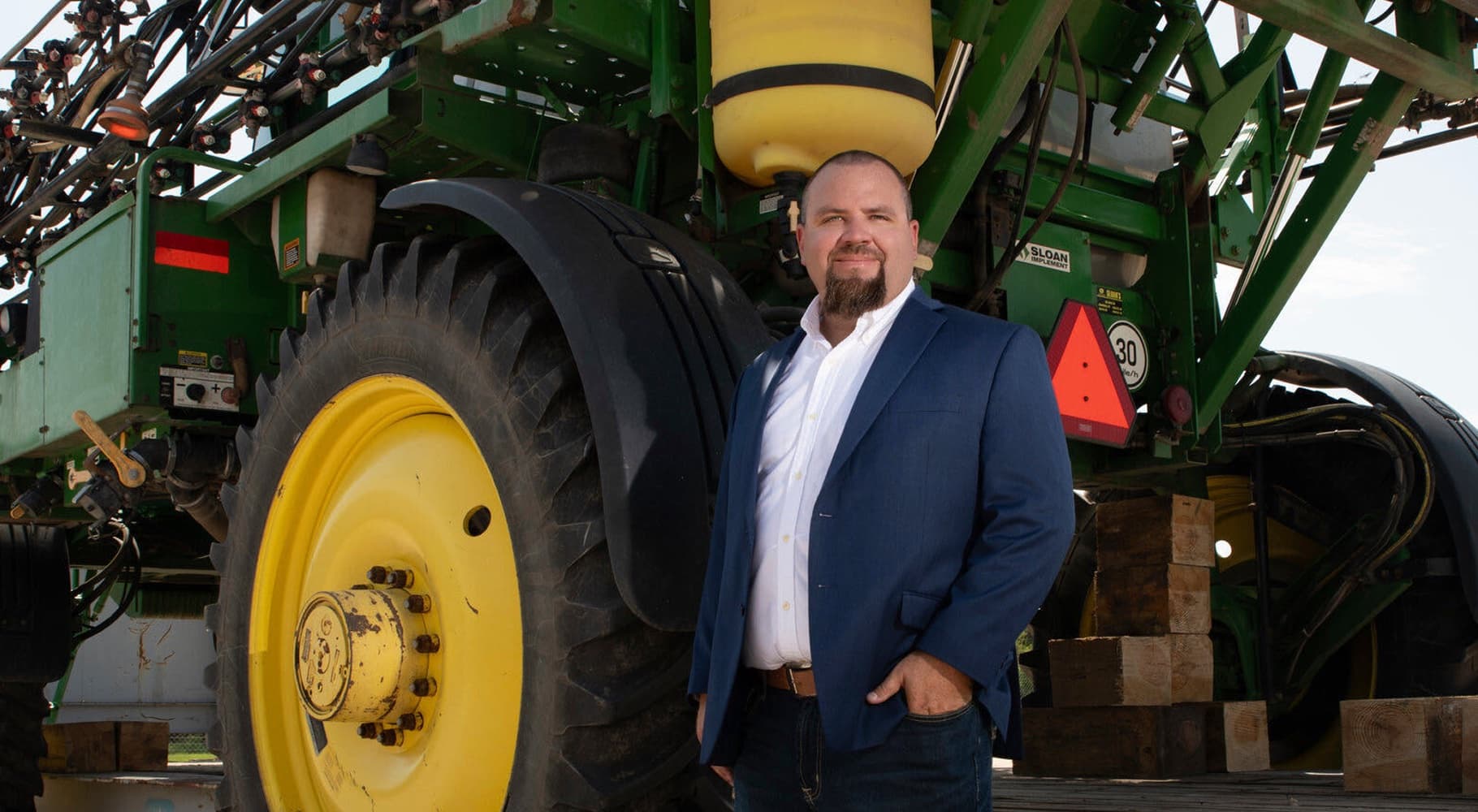 Atlantic Heavy Loaders team member in front of a self-propelled sprayer staged for export