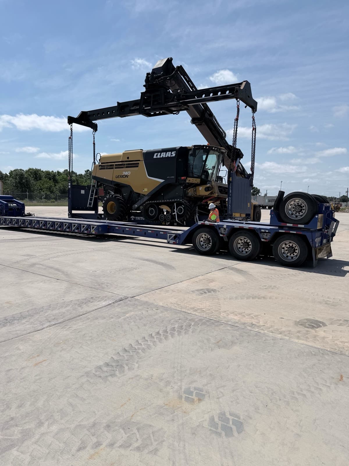 Harvester lowered onto the flat rack, tracks aligning to the deck