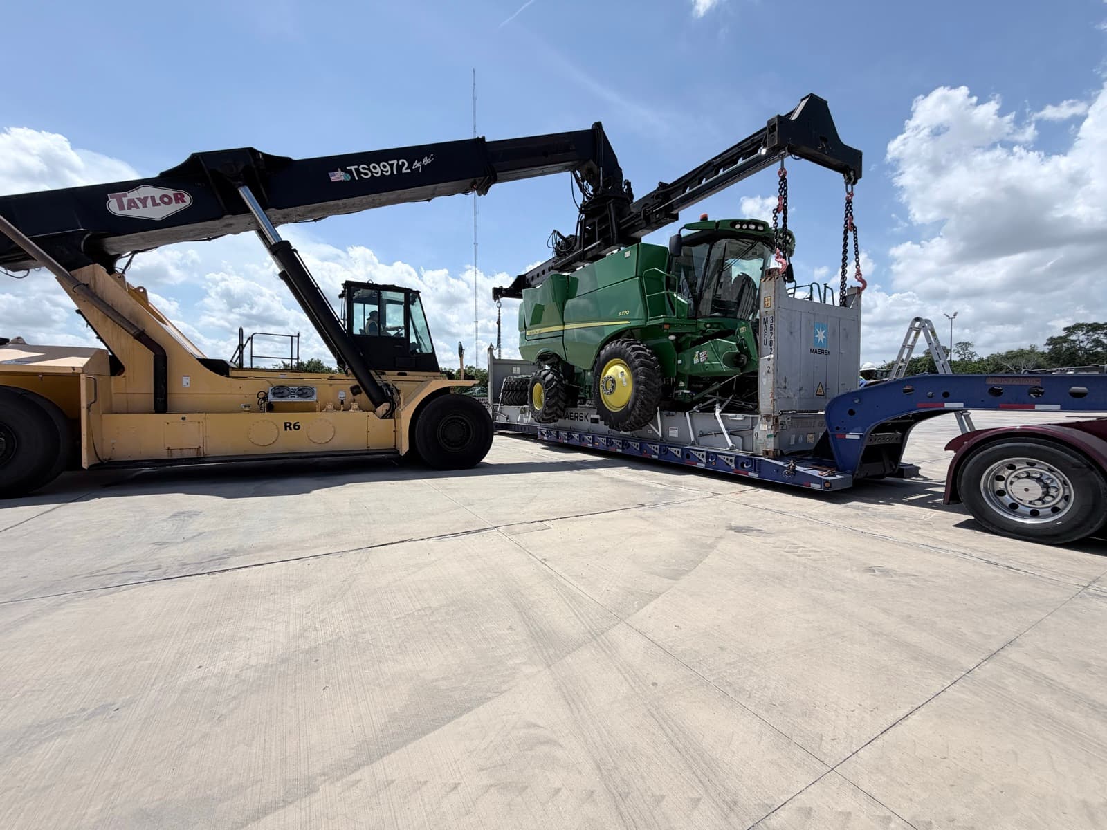 Combine on the trailer with the reach stacker set up alongside to lift