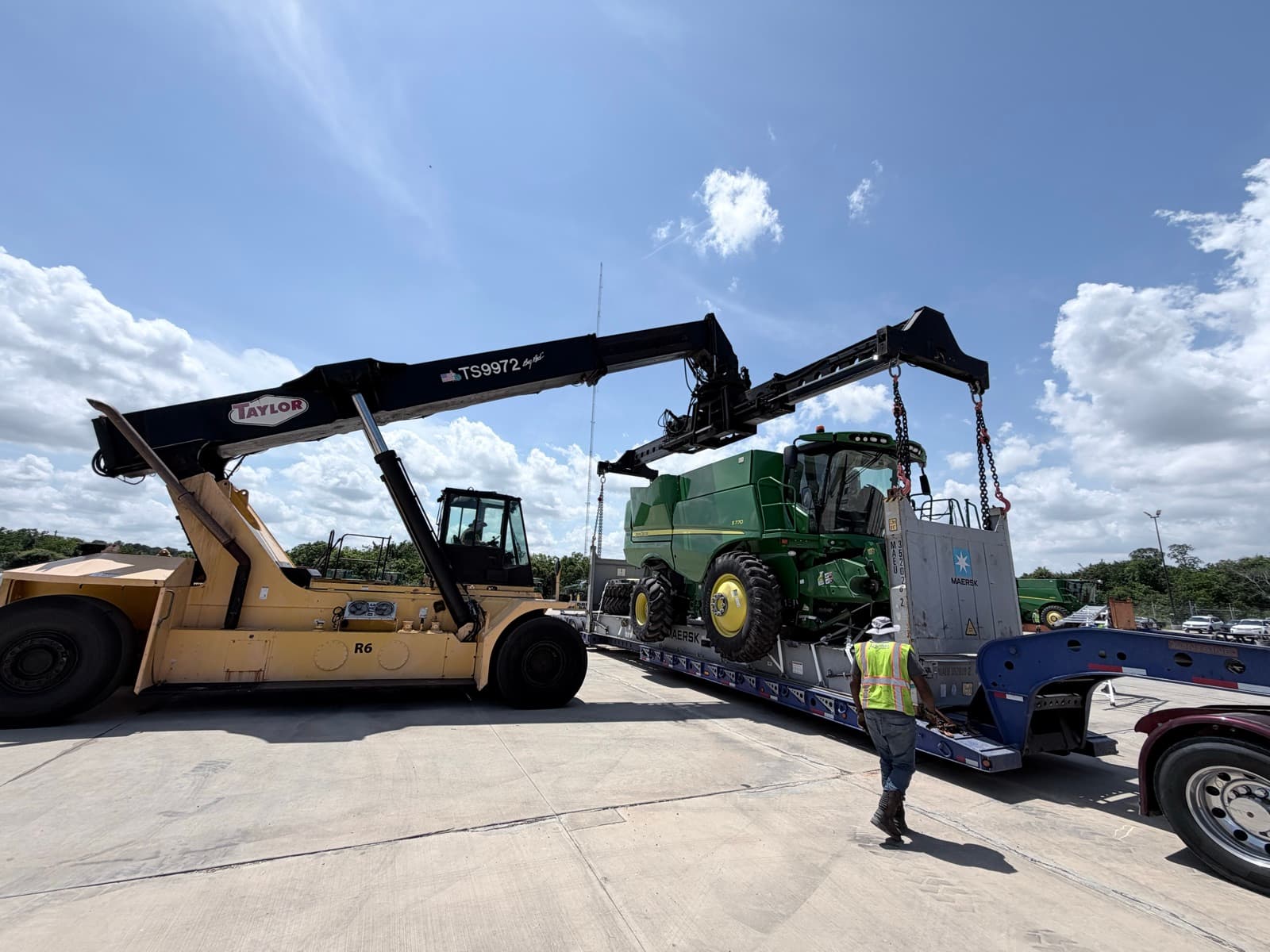 Ground crew guiding the lift as the combine comes off the trailer deck