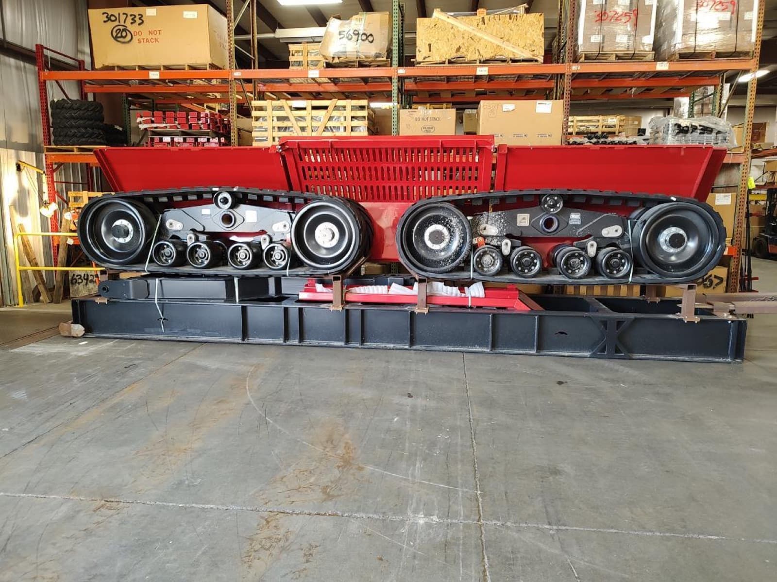 Both track undercarriage sections separated from the machine and staged on beams in the shop