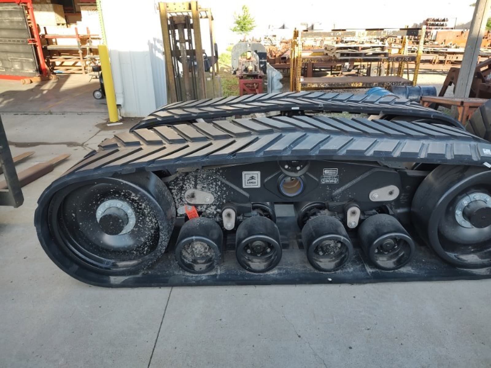 A single crawler track assembly clear of the machine, standing on its own in the yard