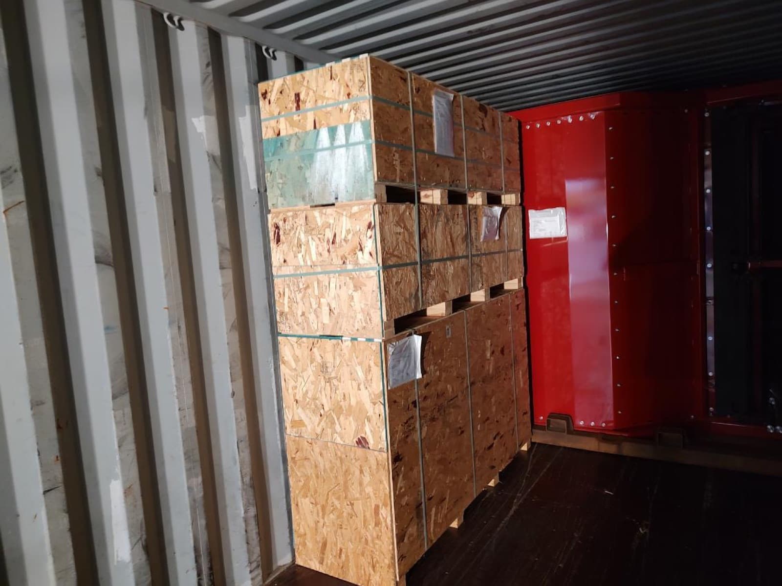 Crated components loaded alongside the machine sections for the final load