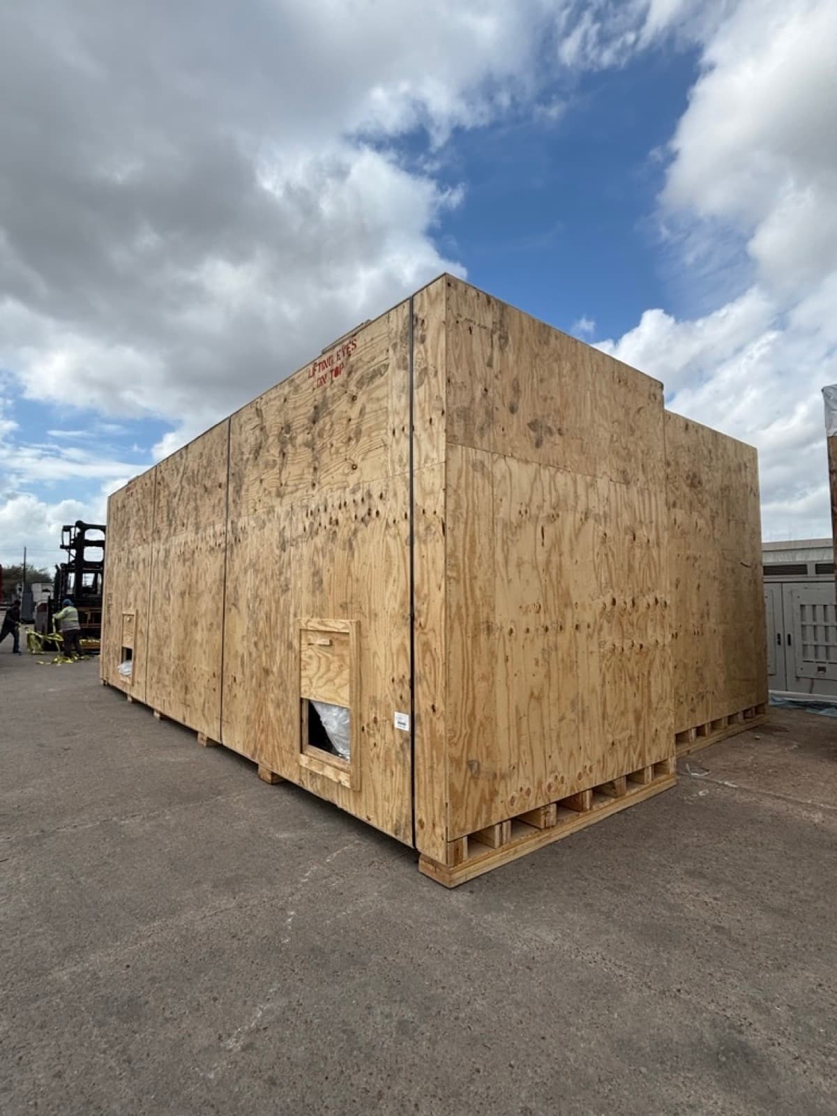 Oversized plywood crate built around the compressor package, access panel fitted into the wall