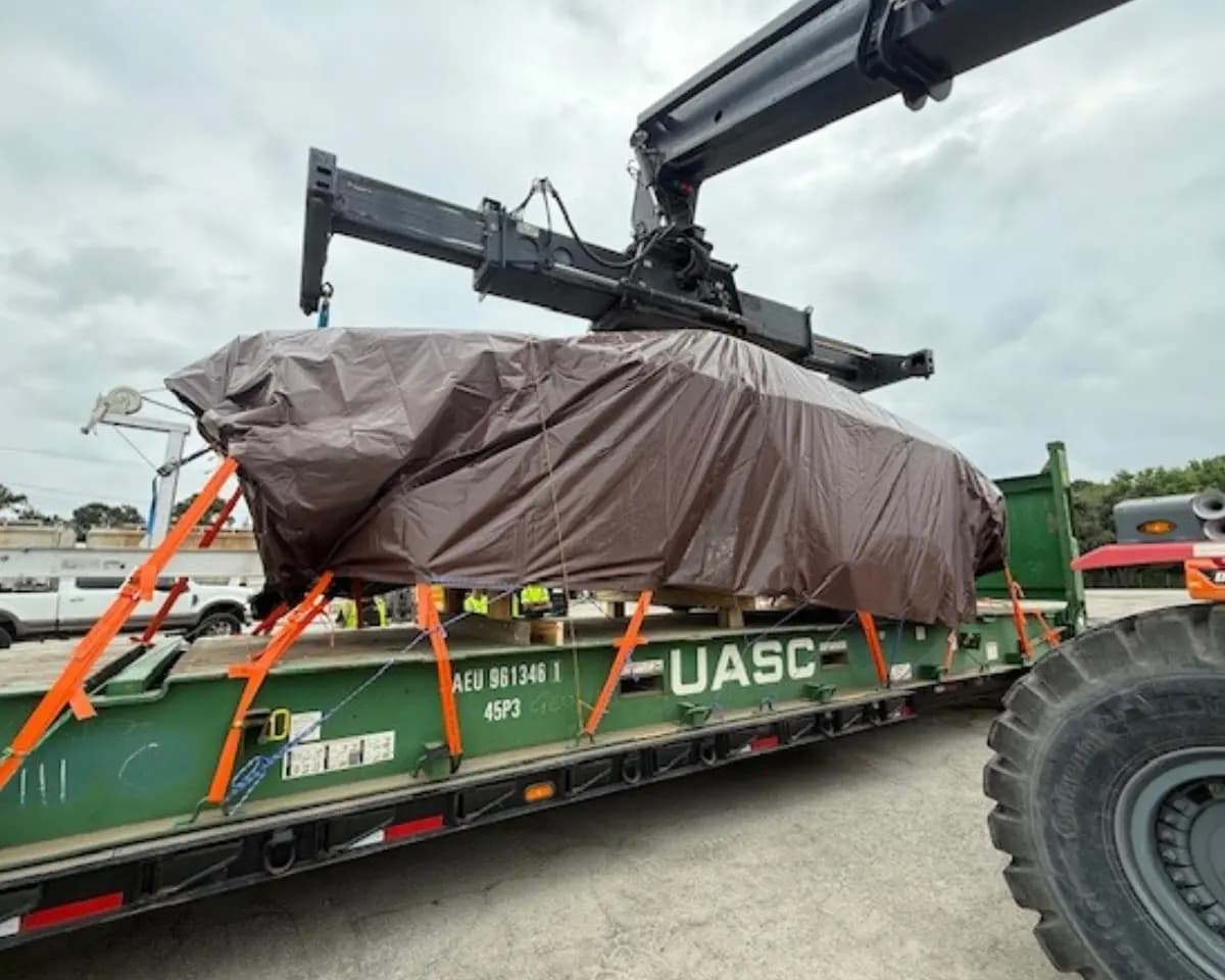 Heavy equipment secured on flat rack for export.