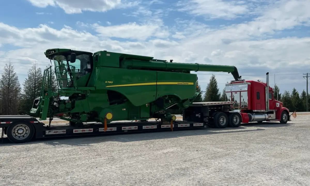 A combine harvester on a lowboy trailer behind a heavy-haul tractor.