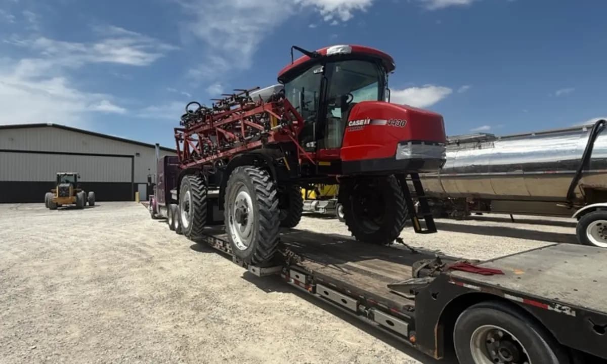 A self-propelled sprayer loaded onto a step-deck trailer at the yard.