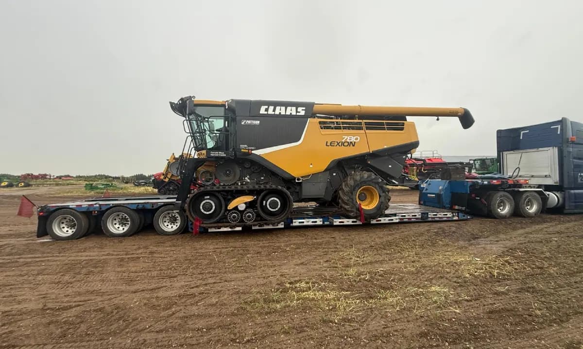 A CLAAS Lexion combine secured on a lowboy trailer in the field.