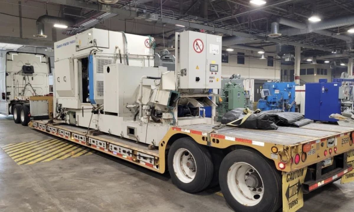 Plant machinery loaded on a lowboy trailer inside the facility.