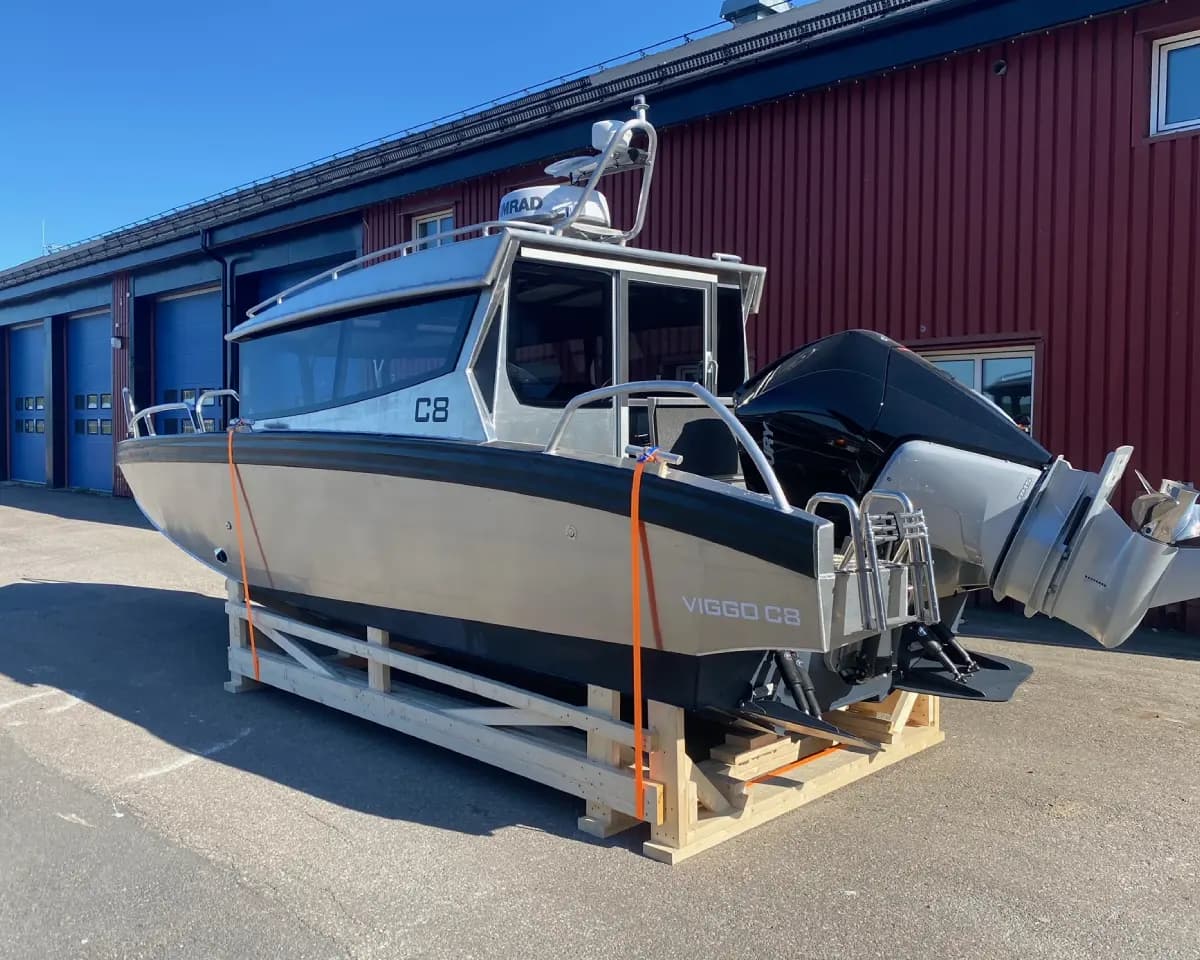 An aluminium cabin boat blocked and cradled beside the workshop.