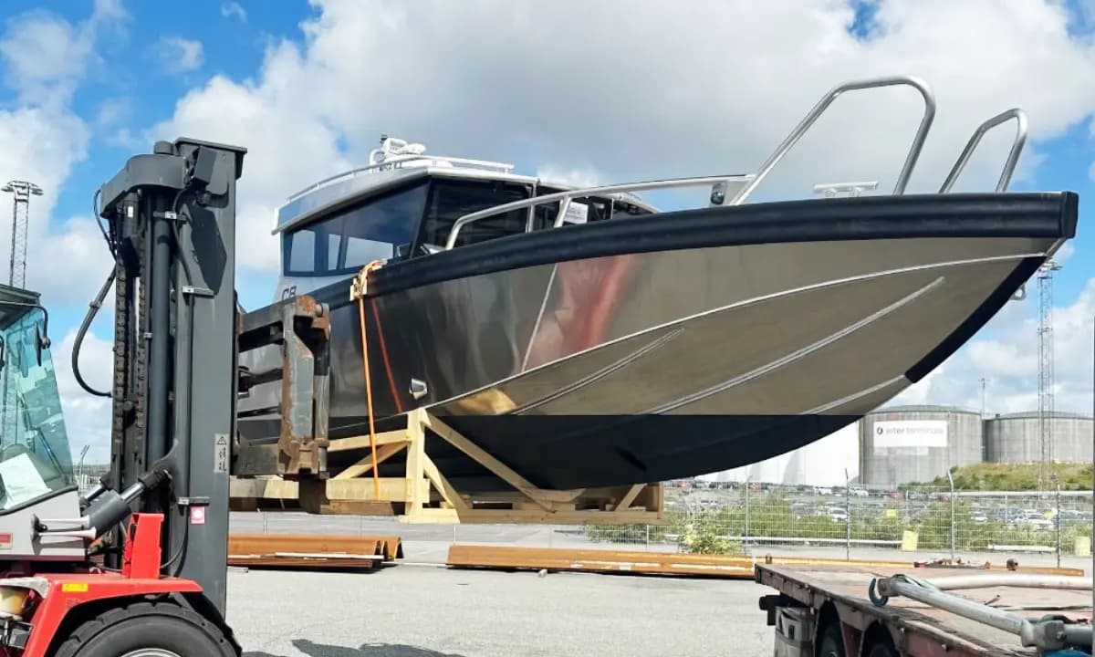An aluminium boat lifted by forklift onto timber bearers.