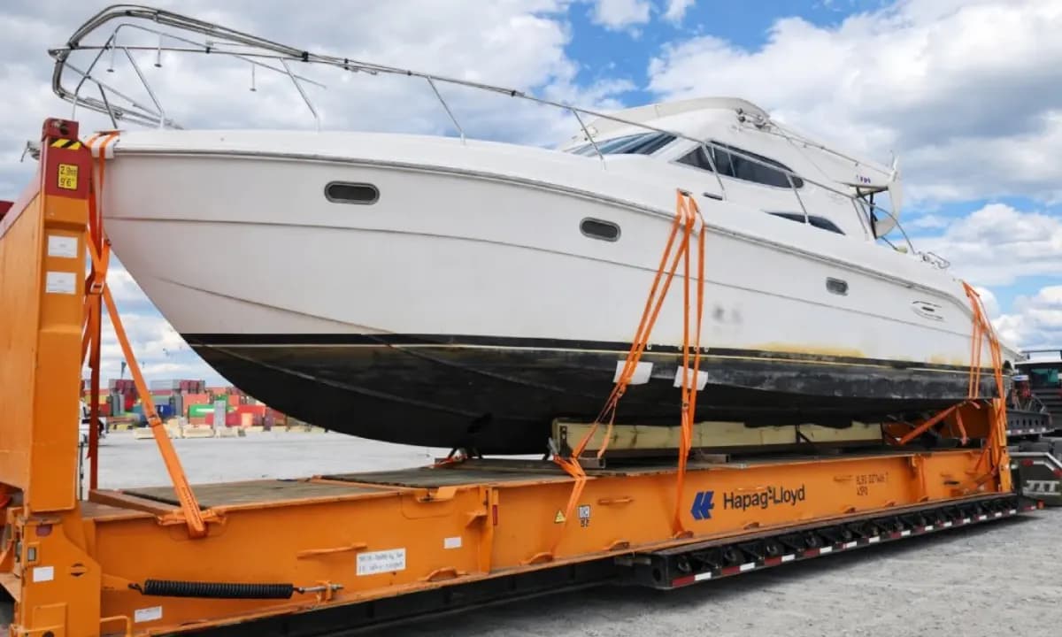 A motor yacht strapped down on an orange flat rack.